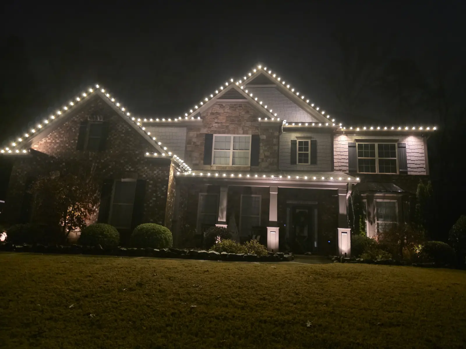 Warm-white roofline holiday lights after installation, Brookstone Country Club, Acworth, photographed at night on November 25, 2025.