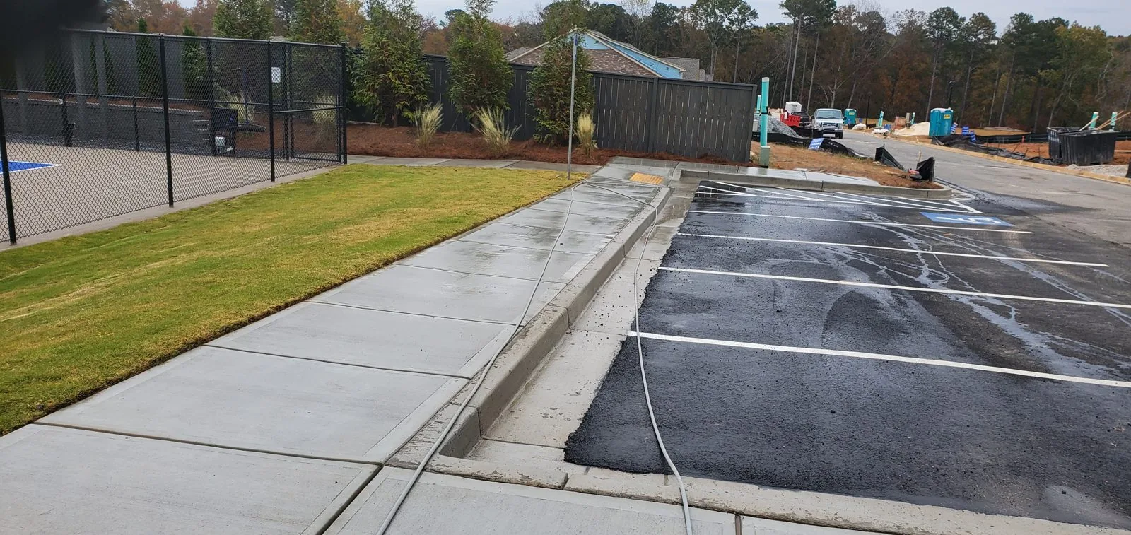 Crew member guiding a round surface cleaner over a concrete driveway at Chattahoochee Bluffs, with dark staining still on the concrete (November 3, 2021)