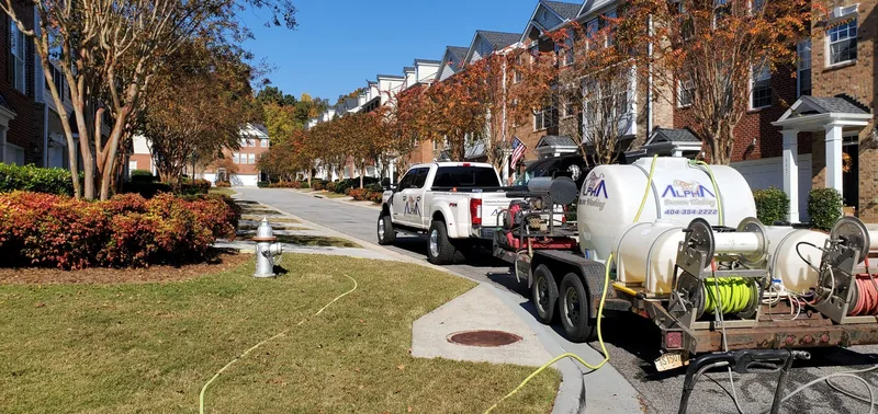 Two crew members cleaning a concrete driveway between houses at Chattahoochee Bluffs, with a red company truck parked behind them (November 10, 2021)